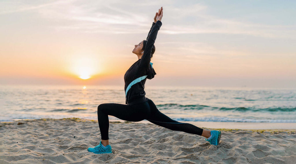 Woman stretching on beach in workout gear