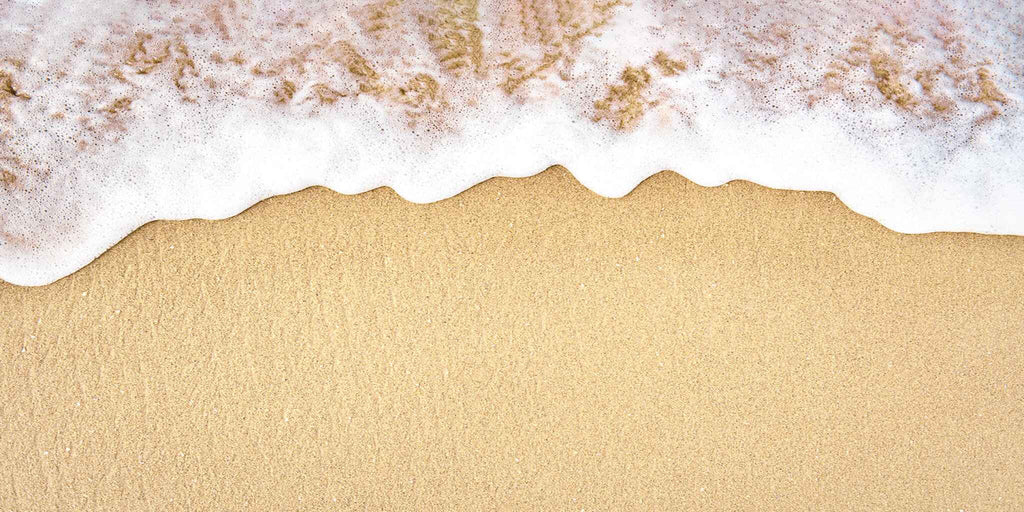Ocean wave foam on beach sand 